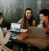 three people sitting in front of table laughing together